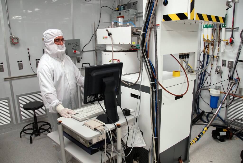 A researcher in a clean suit works in a semiconductor cleanroom