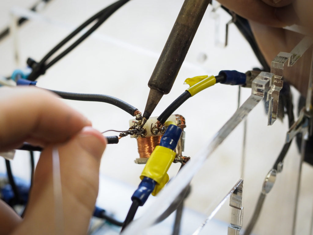 Hands connect wires and components on an electronics project