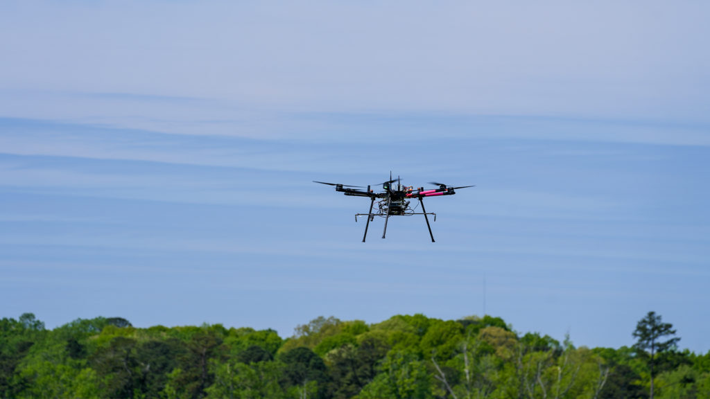 A research drone flies above a tree line