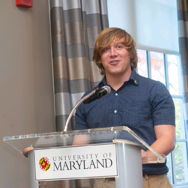 Young man speaking at a University of Maryland podium during an event.
