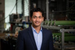 Business professional in a suit standing in an industrial setting, conveying confidence and expertise.