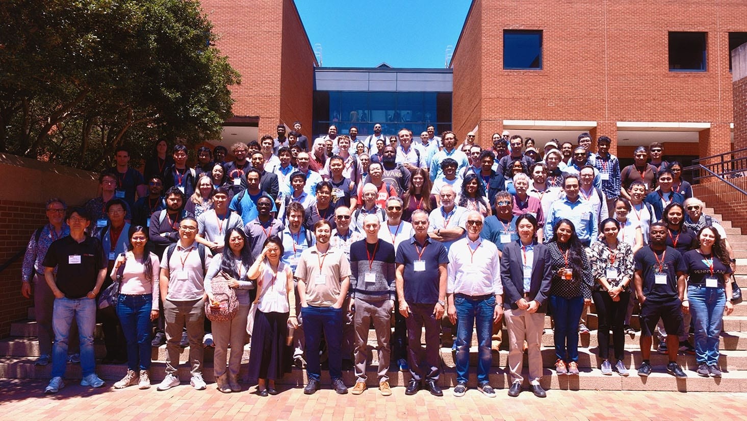 a large group of people stand together on an exterior brick staircase during a sunny day